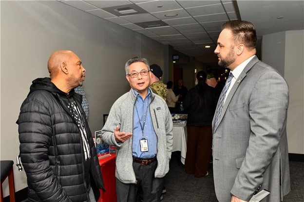 Three men having a conversation at the New England Veteran Experience Action Center.